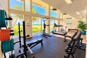 Un gimnasio con equipamiento de ejercicio, una cinta de correr y vistas al exterior.
