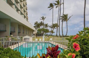 Une piscine entourée de palmiers et un bâtiment doté de balcons.