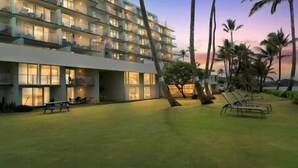 A multi-story hotel with balconies, a grassy courtyard, and palm trees. - Island Life Retreat-Ocean Front-Beach Access (Hauula)