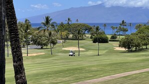 En golfbane med havudsigt og et bjerg i baggrunden.