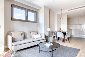 Relax in this serene living space with a sofa, coffee table, and dining area for two.