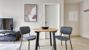 Een moderne woonkamer met een televisie, een eettafel met twee stoelen en een minimalistische inrichting.