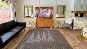 Ein modernes Schlafzimmer mit einem großen Bett, einer Holzkommode, einem schwarzen Sofa, einem Esstisch mit Stühlen und einer Küchenzeile mit einer Mikrowelle.