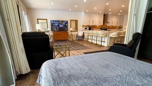 Ein Hotelzimmer mit einem großen Bett, einem Fernseher, einem Schreibtisch und einer Küchenzeile.