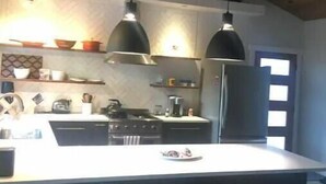 A modern kitchen with pendant lighting, a large island, and bar stools.