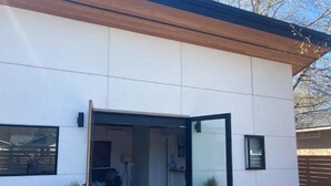 A modern house with a large sliding glass door leading to a patio area.