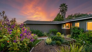A modern house with a well-maintained garden, a palm tree, and a sunset sky. - Barefoot Retreat - Upscale Living on the Mesa (Santa Barbara)
