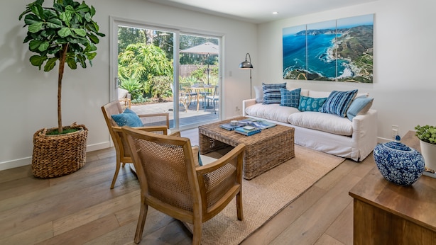 A modern living room with a white sofa, blue and white cushions, a coffee table, and a large plant. - Barefoot Retreat - Upscale Living on the Mesa (Santa Barbara)