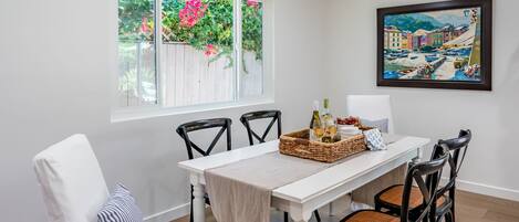 A dining area with a white table, black chairs, and a painting on the wall.
