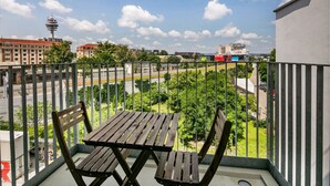 A balcony with a wooden table and chairs, overlooking a cityscape with buildings and a tower. - Elegant Landstraße 1BR w/ Elevator & Playglound, Calm Area, by Blueground (Vienna)
