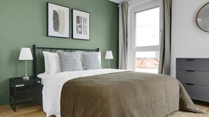 A bedroom with a bed, two bedside tables with lamps, a headboard, a window with curtains, and two framed artworks on the wall. - Sunlit Landstraße 1BR w/ Elevator & Playglound, Calm Area, by Blueground (Vienna)