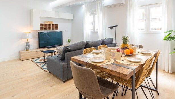 Un salon moderne avec un canapé, une table à manger et un téléviseur.