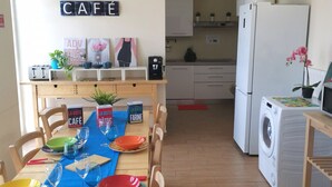 A compact kitchen with a dining area, a washing machine, and a refrigerator.