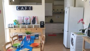 A compact kitchen with a dining area, a washing machine, and a coffee machine.