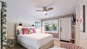 Une chambre à coucher avec un lit, un ventilateur de plafond, une fenêtre et une porte.