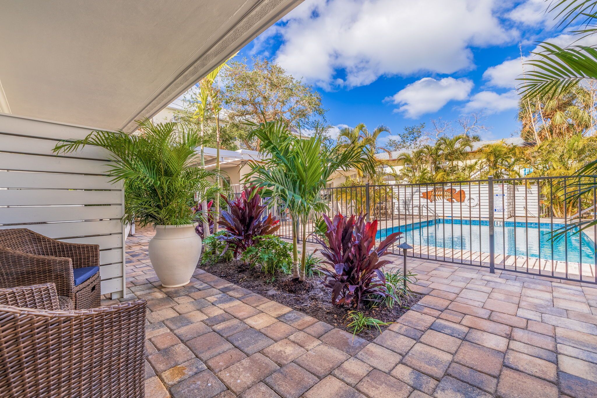 Un patio con mobiliario de mimbre, una maceta grande y una piscina.