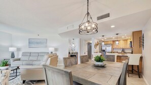Un salon moderne comprenant un coin repas, une cuisine et une petite table à manger avec des chaises.