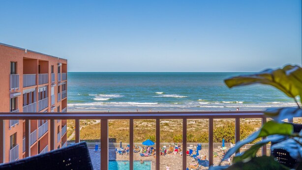 Un hôtel situé en bord de mer, doté d’une piscine, de chaises longues et de parasols.
