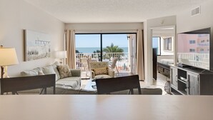 Een hotelkamer met balkon, een eethoek, een televisie en een schilderij aan de muur.
