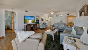 Amplia sala de estar con un televisor de pantalla plana grande, asientos cómodos, una zona de cocina y un comedor.