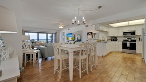 Una cocina amplia con armarios blancos, un comedor con mesa y sillas blancas, y un ventilador de techo.