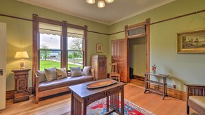 Una habitación con un banco de madera, una mesa con bandeja, una lámpara y una ventana con vista al exterior.