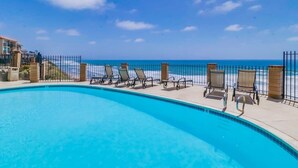 Una piscina con sillones de descanso y vista al océano.