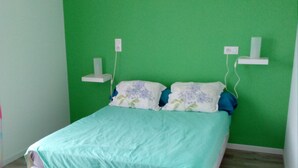 A bed in a room with green walls and a wooden floor. - Léon: New House With Heated Pool and Private ; Handi-accessible (Léon)