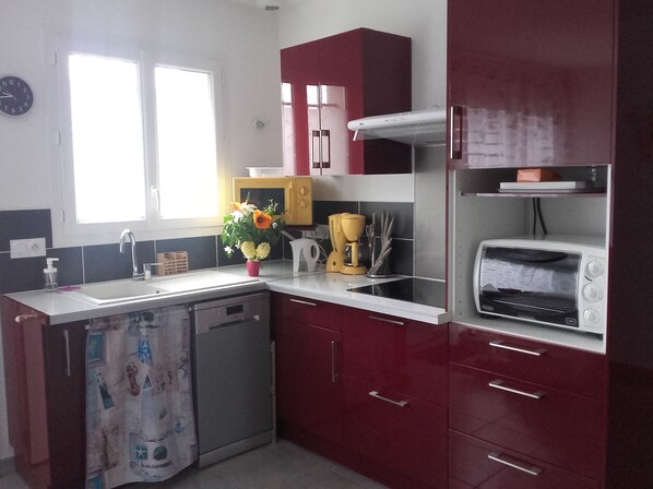A compact kitchen with a dishwasher, a microwave, a toaster, and a sink.