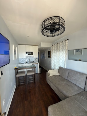 A modern living space with a kitchen, dining area, and a gray sofa.