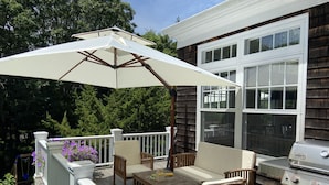 An outdoor patio with a table and chairs, a grill, and a white umbrella. - Pristine Southampton Home (Water Mill)