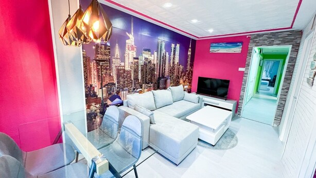 A modern living room with a cityscape mural, a sectional sofa, a glass coffee table, and a flat-screen TV. - Immaculate 12-Bed Apartment in Valencia (Valencia)
