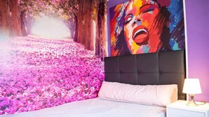 A bedroom with a bed, a nightstand, a lamp, and a large wall mural. - Immaculate 12-Bed Apartment in Valencia (Valencia)