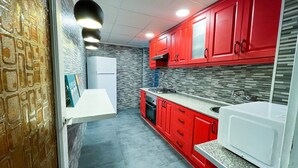 A modern kitchen with red cabinets, a white refrigerator, and a built-in oven. - Immaculate 12-Bed Apartment in Valencia (Valencia)
