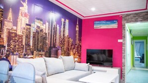 A modern living room with a cityscape mural, a white sofa, and a flat-screen TV. - Immaculate 12-Bed Apartment in Valencia (Valencia)