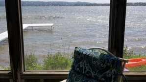 A view from a window overlooking a body of water with a bench and a cushion on the window sill.