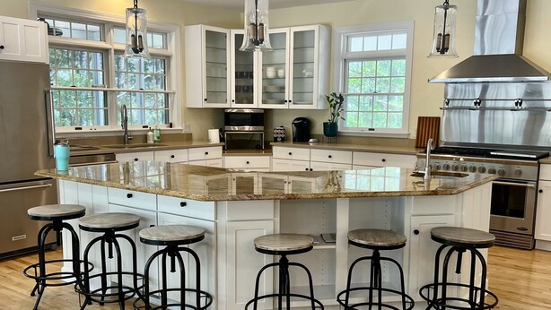 A modern kitchen with white cabinets, a large island with stools, stainless steel appliances, and large windows. - Close to the beach! A great multi family home with loads of ammenties.  (Bethany Beach)