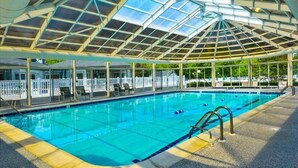 A swimming pool with a glass ceiling, surrounded by a white fence and lounge chairs. - Close to the beach! A great multi family home with loads of ammenties.  (Bethany Beach)