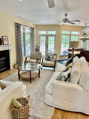A spacious living room with a fireplace, comfortable seating, and large windows.