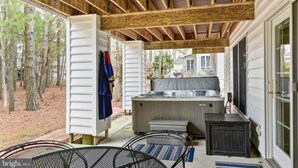 An outdoor covered patio with a hot tub, seating area, and a view of a house in the background. - Close to the beach! A great multi family home with loads of ammenties.  (Bethany Beach)