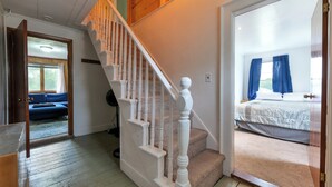A staircase leading to a bedroom with a bed and blue curtains.