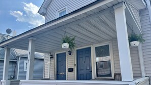 A two-story house with a covered porch, two doors, and a small window. - BRADLEY BEACH HOUSE with Private Backyard  (Bradley Beach)