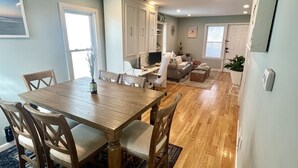 A spacious living area with a wooden dining table, chairs, a sofa, and a TV. - BRADLEY BEACH HOUSE with Private Backyard  (Bradley Beach)