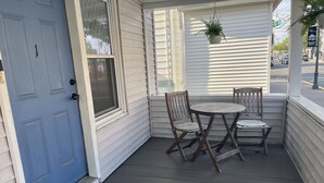 A porch with a blue door, a small table with two chairs, and a potted plant. - BRADLEY BEACH HOUSE with Private Backyard  (Bradley Beach)