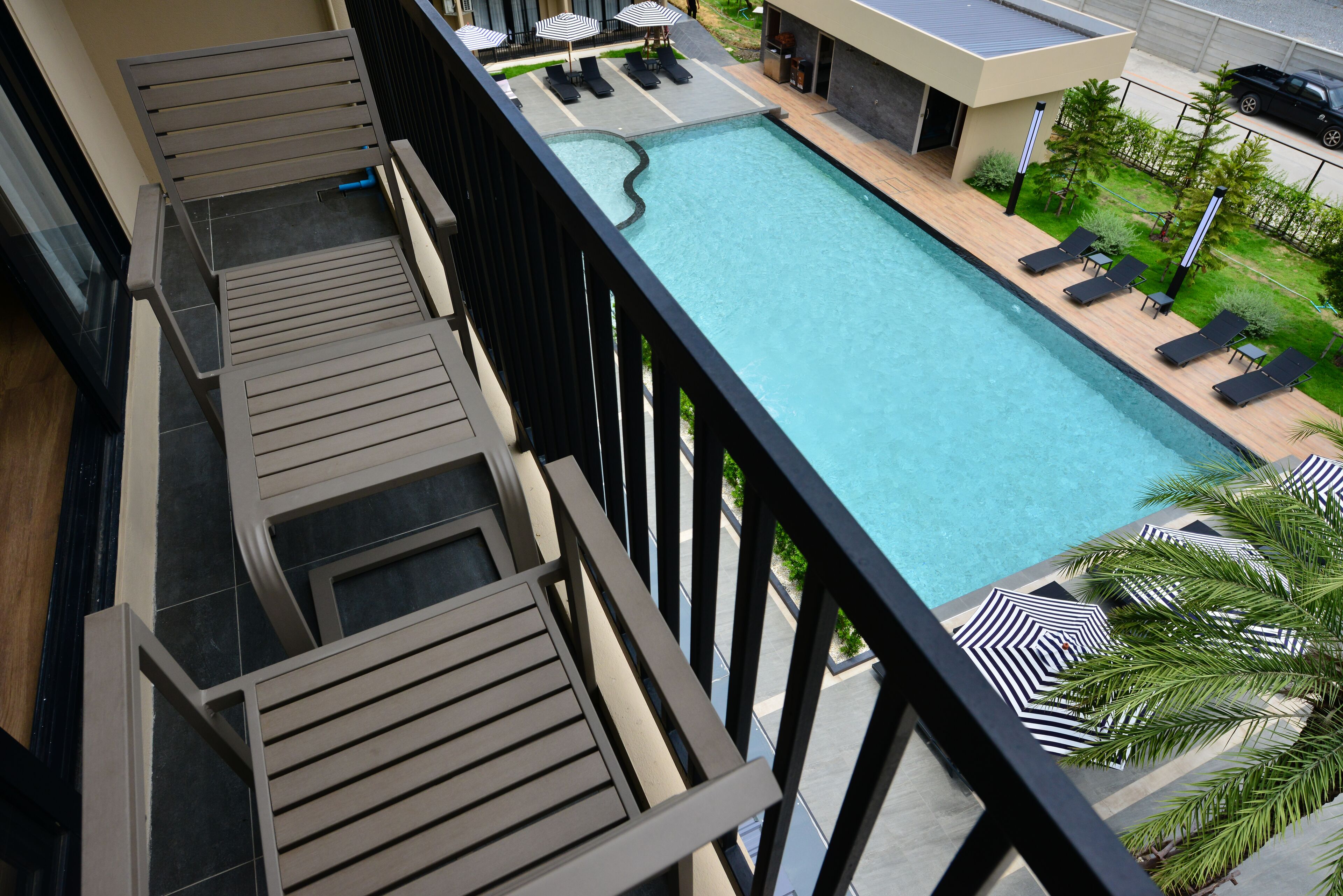 A rooftop pool with lounge chairs and umbrellas, surrounded by a modern building.
