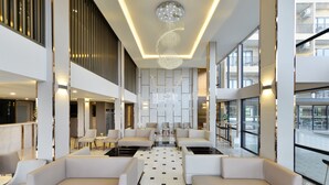 A spacious lobby with modern seating, a central chandelier, and large windows offering views of the outside. - Grand BS Airport Hotel Suvarnabhumi (Bangkok)
