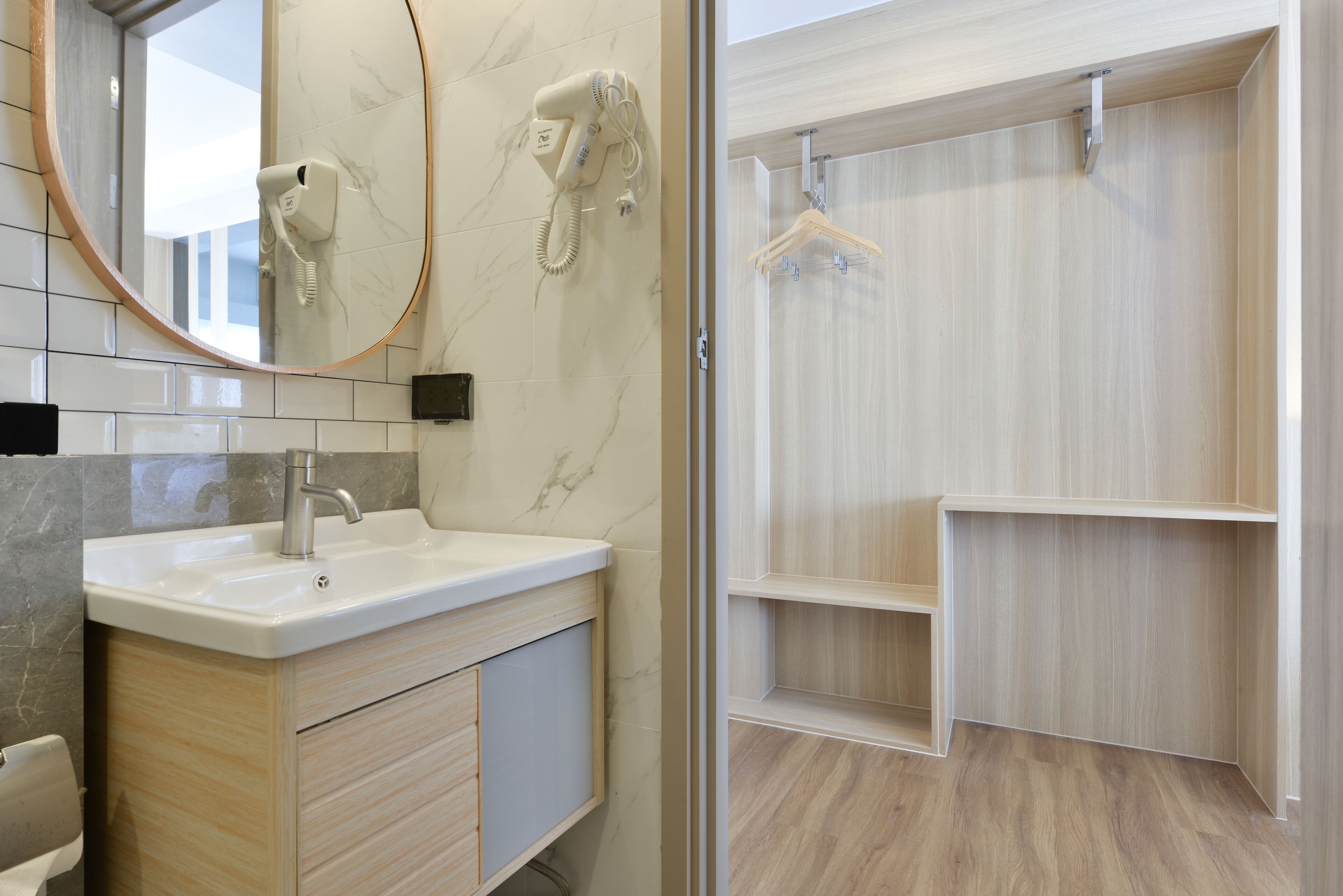 A bathroom with a marble sink, a hairdryer, and a wooden vanity.