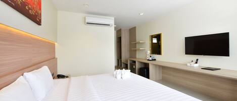 Ein Hotelzimmer mit einem großen Bett, einem an der Wand befestigten Flachbildfernseher, einem Holz-Kopfschild und einem Nachttisch mit Telefon und Lampe.