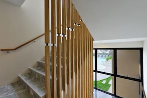 A staircase with a wooden railing and a view of a pool area through a glass door. - Grand BS Airport Hotel Suvarnabhumi (Bangkok)