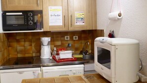 A kitchen with wooden cabinets, a microwave, a coffee maker, a toaster, and a dishwasher. - Studio 2 cabins 4 pers. pets allowed, private parking (Valloire)